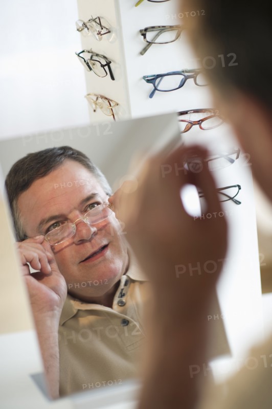 USA, New Jersey, Jersey City, Man trying on glasses in shop mirror.