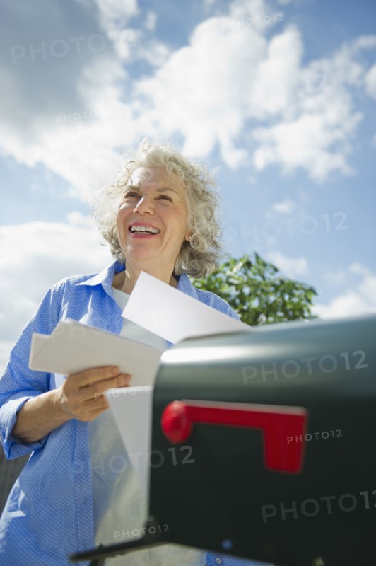 USA, New Jersey, Jersey City, Senior woman checking mail at mailbox.