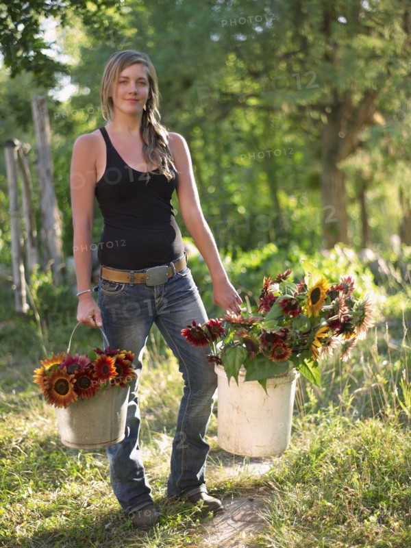 USA, Colorado, Young woman carrying buckets with sunflowers. Photo : John Kelly