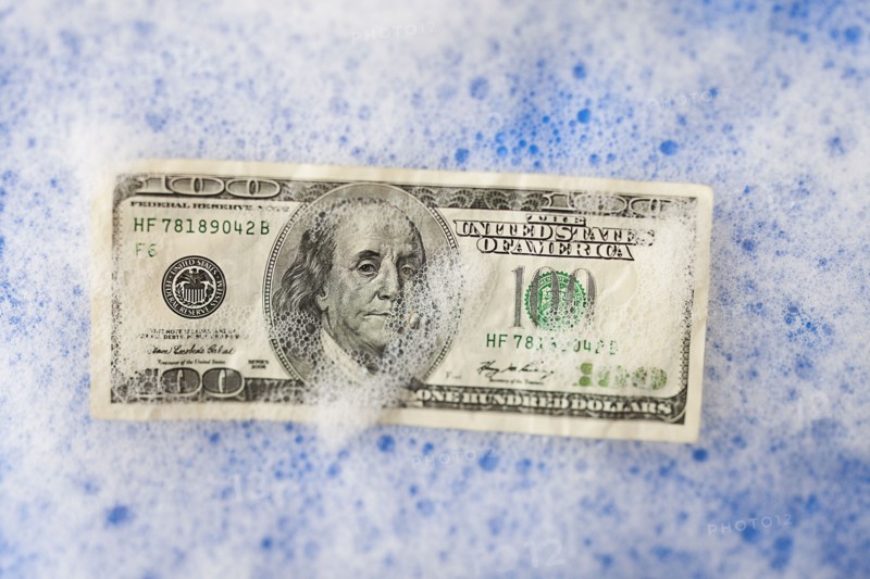 One hundred dollar bill soaking in soap sud. Photo : Mike Kemp