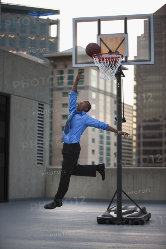 USA, Utah, Salt Lake City, Young businessman scoring basketball goal. Photo : Mike Kemp