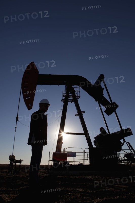 Silhouette of oil worker by pump jack on rig. Photo : Dan Bannister