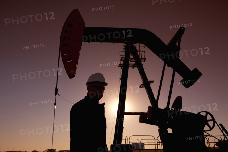 Silhouette of oil worker by pump jack on rig. Photo : Dan Bannister