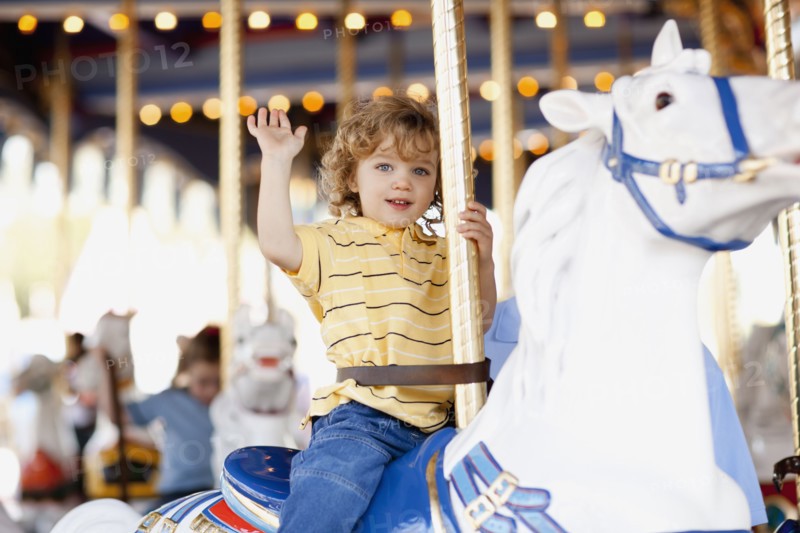 USA, California, Los Angeles, Boy (4-5) sitting on carousel's horse and waving. Photo : FBP