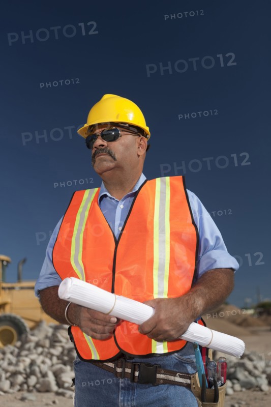Construction worker holding blueprint on building site. Photo : Dan Bannister