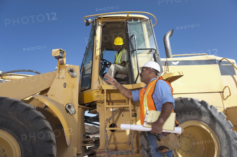 Two construction workers talking by mechanical digger. Photo : Dan Bannister