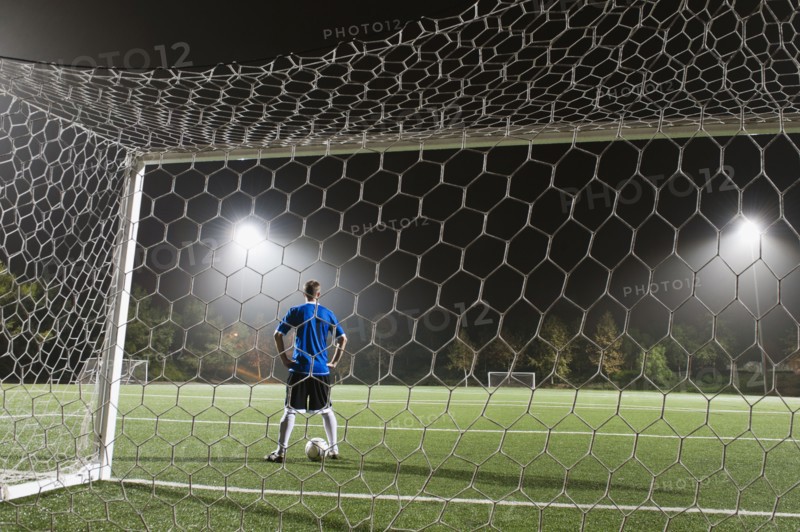 USA, California, Ladera Ranch, goalie on illuminated soccer field at night.