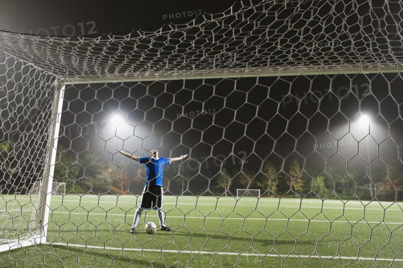 USA, California, Ladera Ranch, goalie on illuminated soccer field at night.