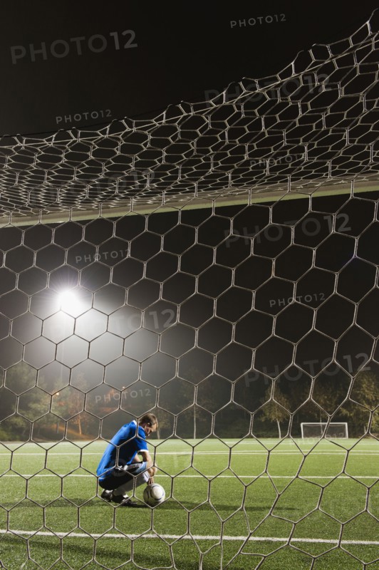 USA, California, Ladera Ranch, goalie on illuminated soccer field at night.
