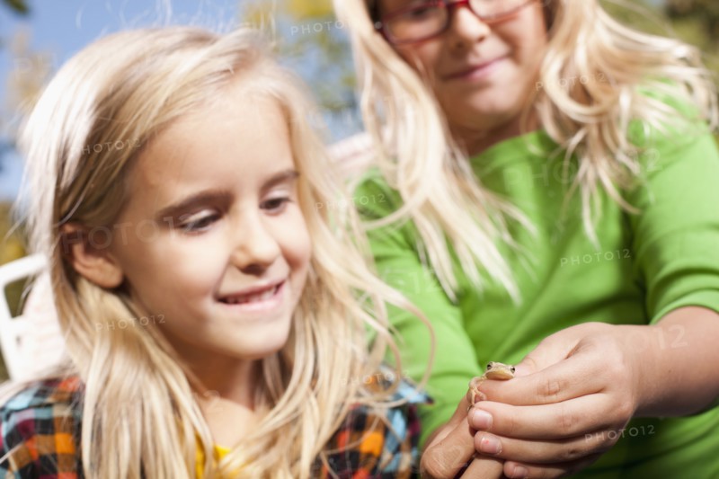 USA, Utah, close up of sisters (6-7, 8-9 ) holding frog. Photo : Tim Pannell