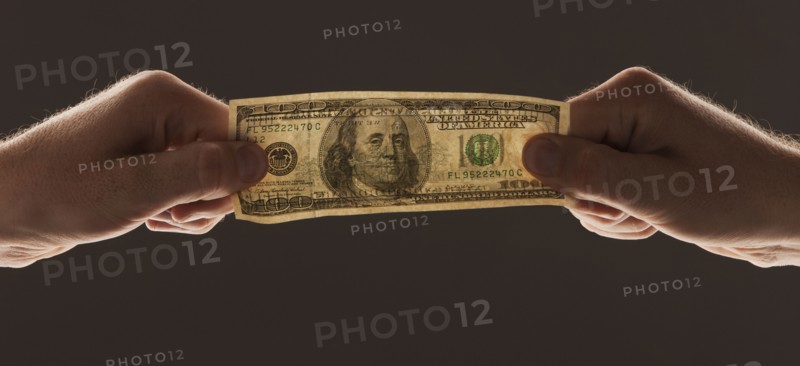 Hands holding one hundred dollar bill. Photo : Mike Kemp