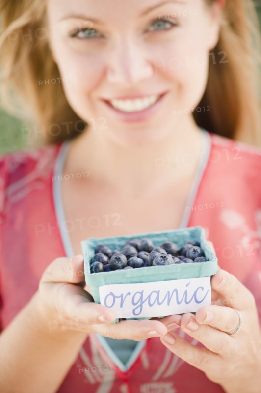 USA, New Jersey, Jersey City, Young attractive woman offering box of blueberries. Photo : Jamie Grill Photography