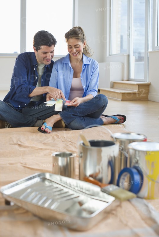 USA, New Jersey, Jersey City, Couple sitting near painting equipment in new home .
