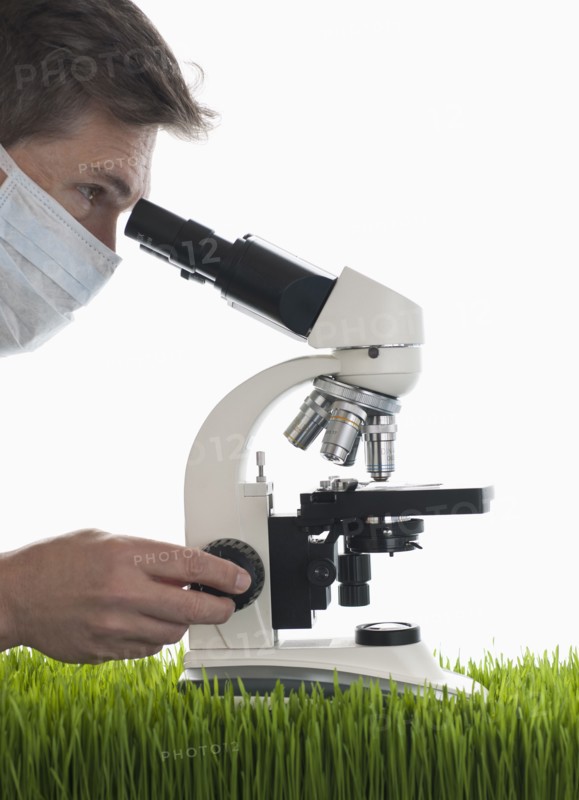 Man looking through microscope in studio.