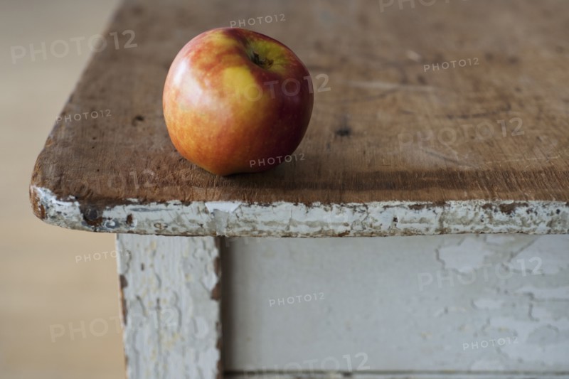 Apple on the egde of table.
