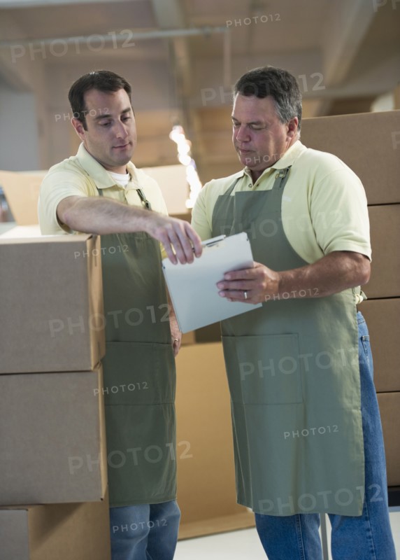 USA, New Jersey, Jersey City, Two male warehouse workers by stacked boxes.