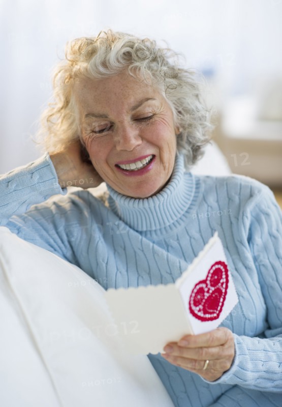 USA, New Jersey, Jersey City, Senior woman reading Valentines card in living room.