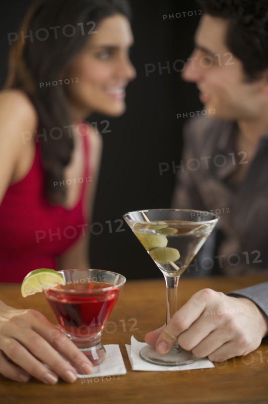 Young couple having drinks and flirting, studio shot.
