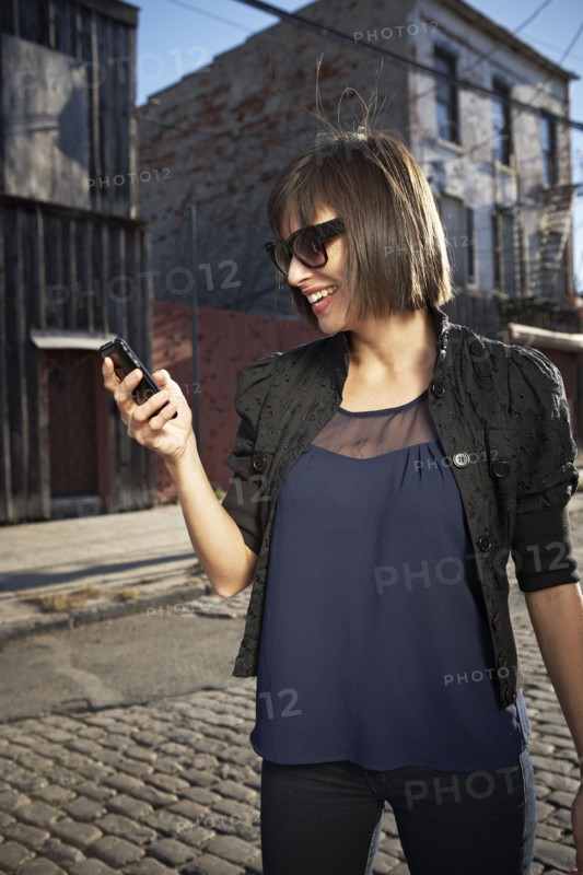USA, New York City, Brooklyn, woman in street using phone. Photo : Shawn O'Connor