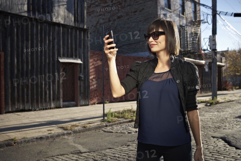 USA, New York City, Brooklyn, woman in street using phone. Photo : Shawn O'Connor