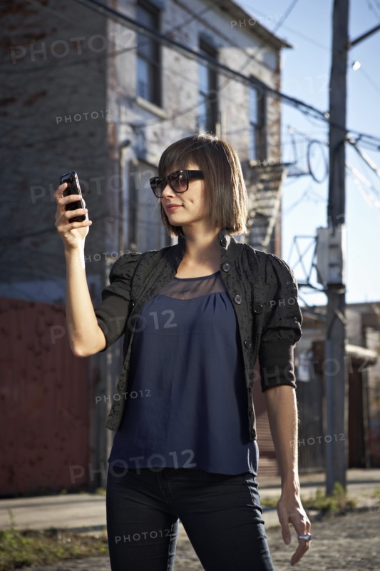 USA, New York City, Brooklyn, woman in street using phone. Photo : Shawn O'Connor