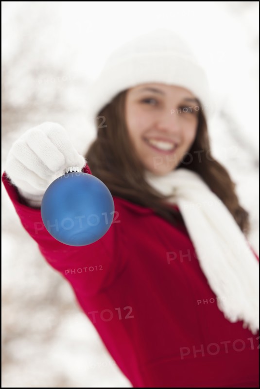 USA, Utah, Lehi, Portrait of young woman holding Christmas bauble outdoors. Photo : Mike Kemp