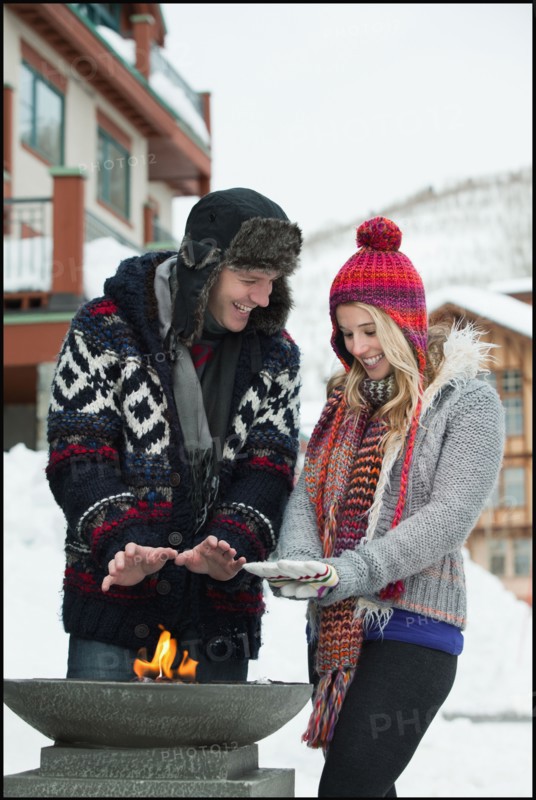 USA, Utah, Salt Lake City, couple warming hands over burner in ski resort. Photo : Mike Kemp