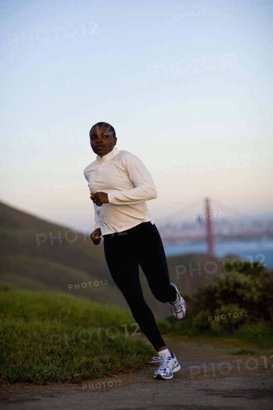 USA, California, San Francisco, Woman jogging, Golden Gate Bridge in background. Photo : Noah Clayton
