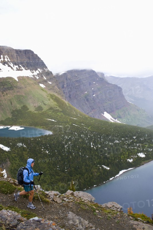 USA, Montana, Glacier National Park, Mid adult woman hiking with backpack during rain. Photo : Noah Clayton