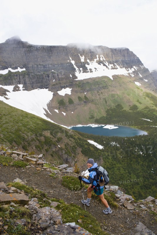 USA, Montana, Glacier National Park, Mid adult woman hiking with backpack during rain. Photo : Noah Clayton