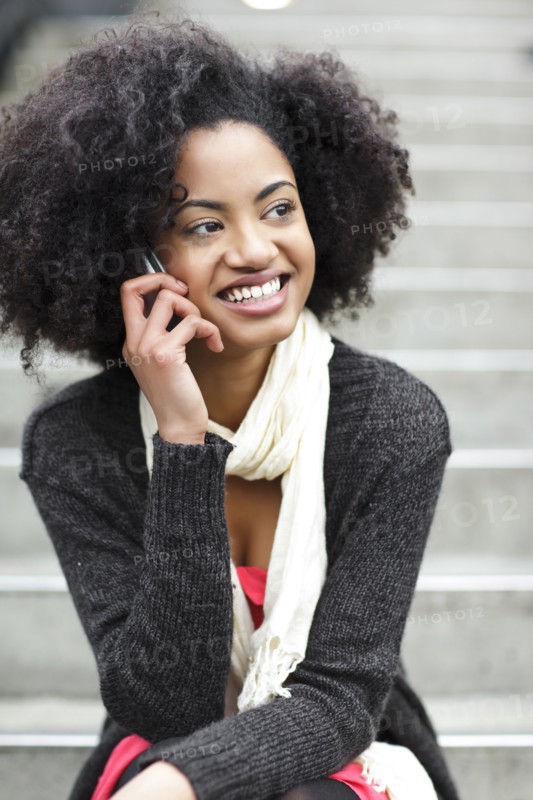 USA, Washington State, Seattle, young woman sitting on steps and talking on mobile phone. Photo : Take A Pix Media