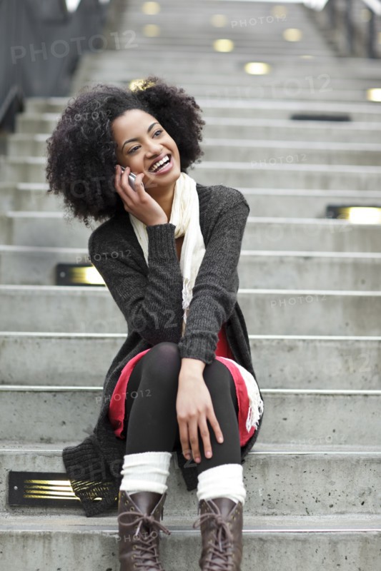 USA, Washington State, Seattle, young woman sitting on steps and talking on mobile phone. Photo : Take A Pix Media