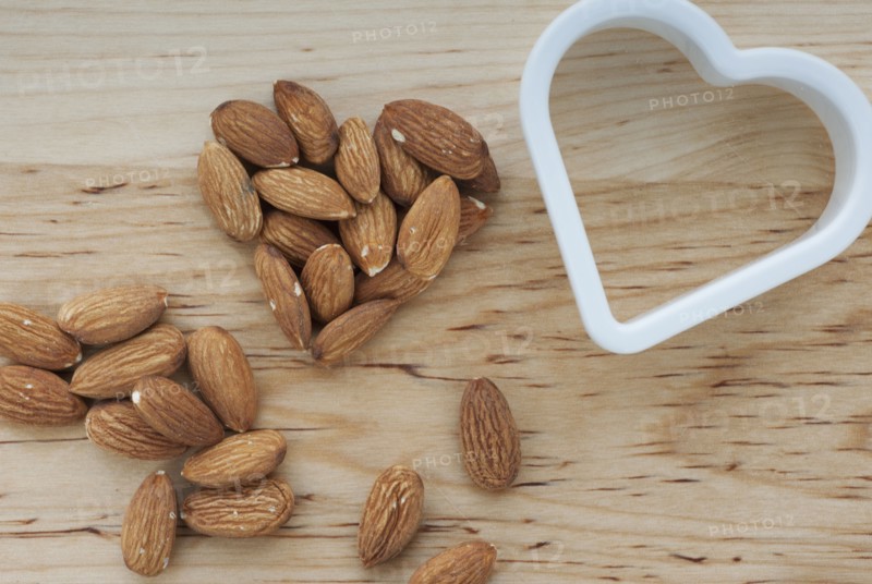 Heart shaped almonds with cutter on chopping board.