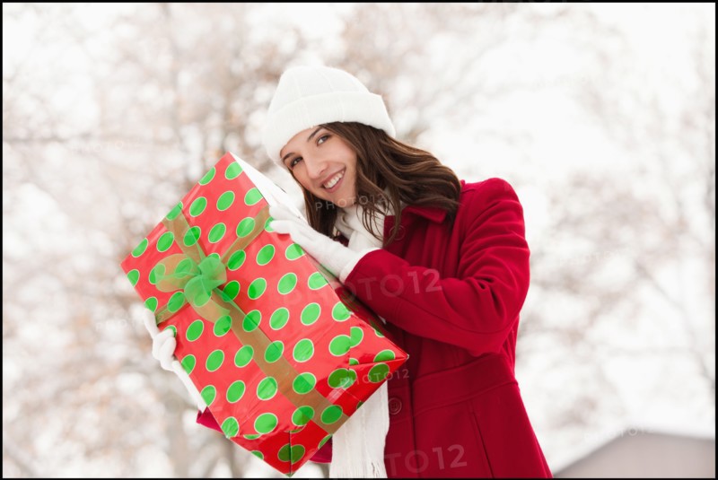 USA, Utah, Lehi, Portrait of young woman holding Christmas gift outdoors. Photo : Mike Kemp