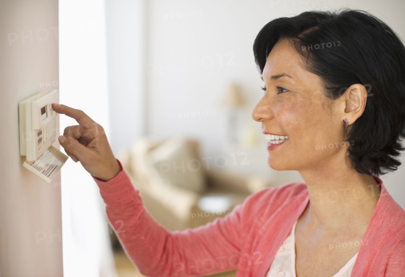 Mature woman adjusting room temperature.