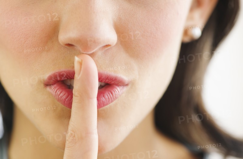 Young woman with finger on lips, close-up.