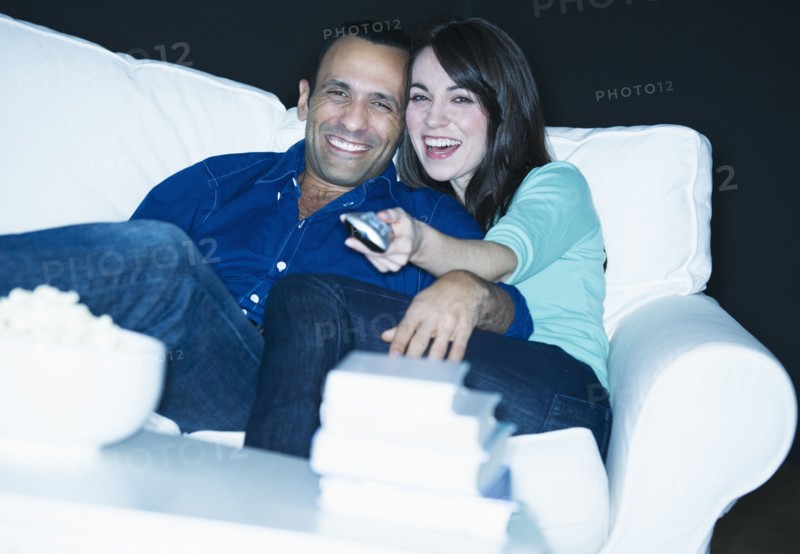 Couple watching television on sofa.