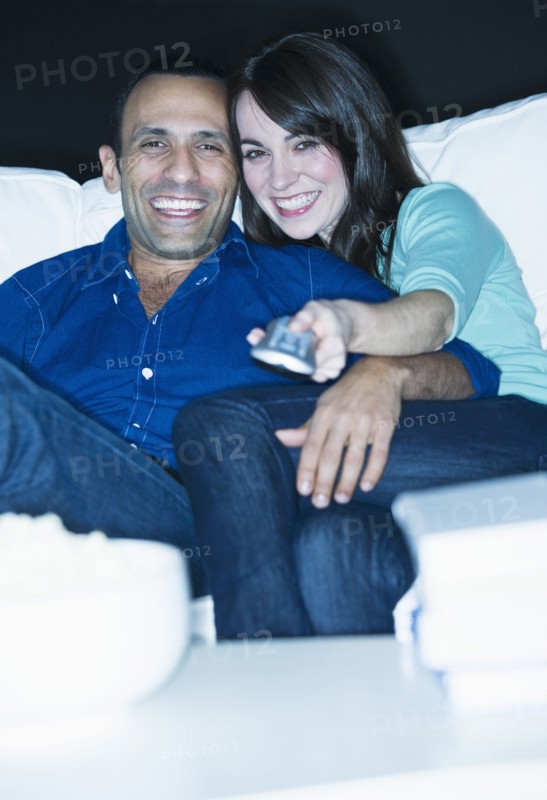 Couple watching television on sofa.
