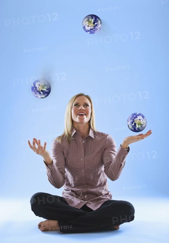 Young woman juggling globes in clouds. Photo : Daniel Grill