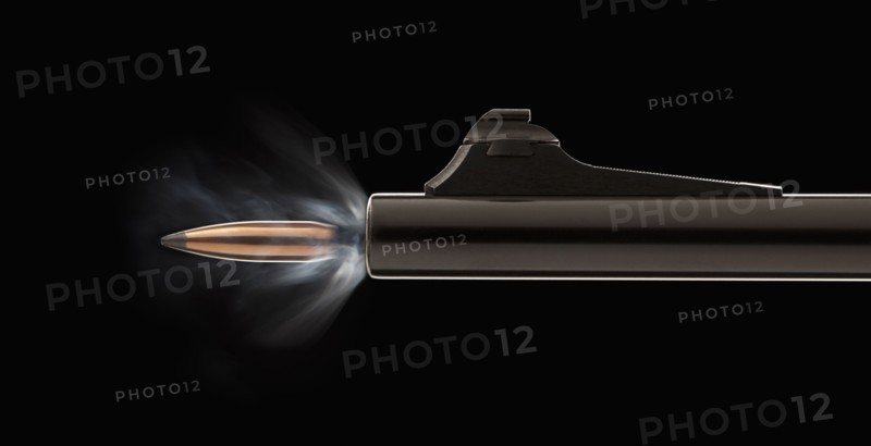 Studio shot of bullet coming out of gun barrel. Photo : Mike Kemp