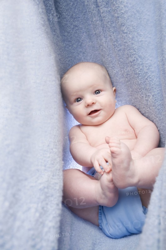 Portrait of baby boy (6-11 months) in bedclothes. Photo : Noah Clayton