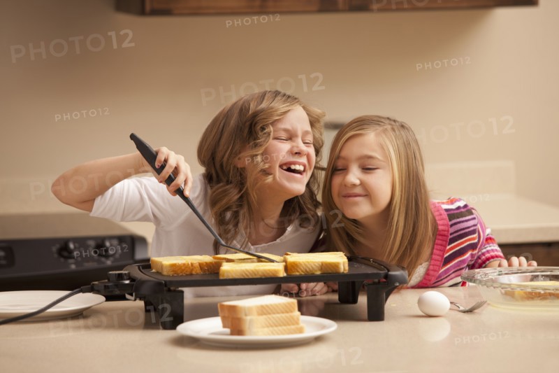 Two girls (10-11) preparing toast in kitchen. Photo : Mike Kemp
