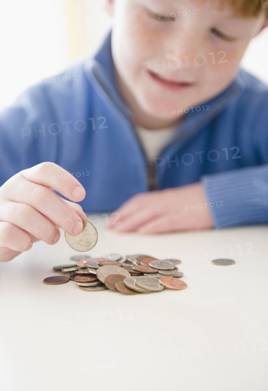Portrait of boy (8-9) counting coins. Photo : Jamie Grill Photography