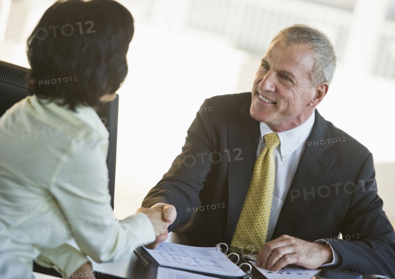 Businesswoman and businessman shaking hands.
