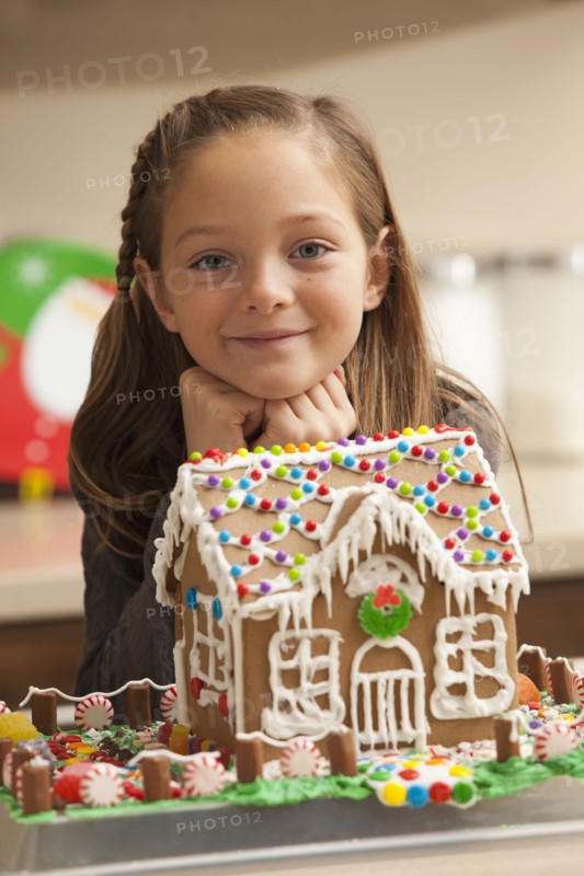 Portrait of girl (6-7) by gingerbread house. Photo : Mike Kemp