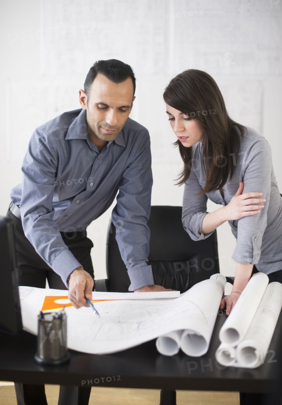 Business man and woman studying blueprints.