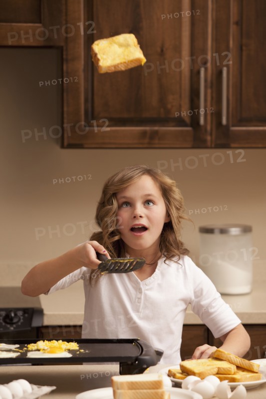 Girl (10-11) flipping toast in kitchen. Photo : Mike Kemp