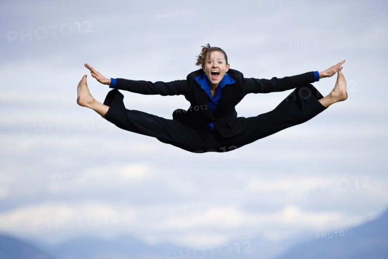 Businessman mid-air doing splits. Photo : Noah Clayton
