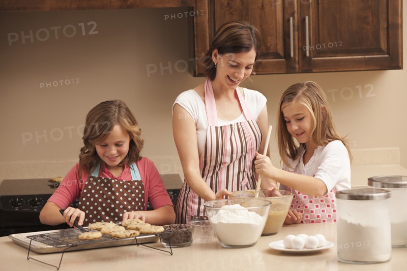 Mother baking with daughters (10-11) in kitchen. Photo : Mike Kemp
