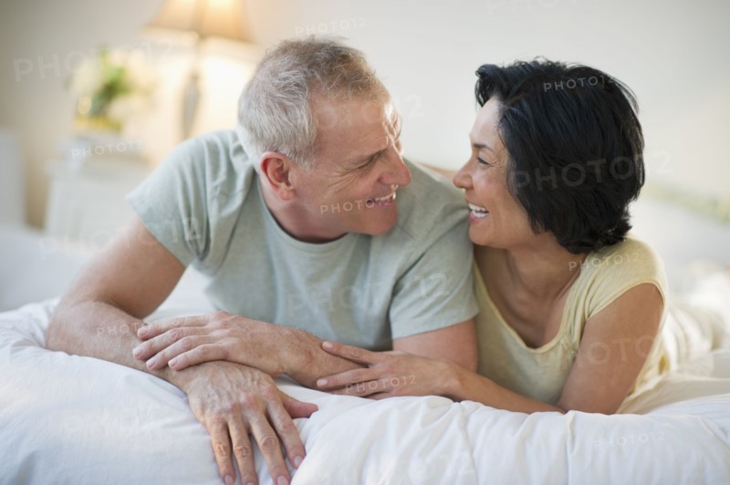 Happy mature couple laying in bed.